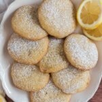 lemon cookies on white platter sprinkled with powdered sugar
