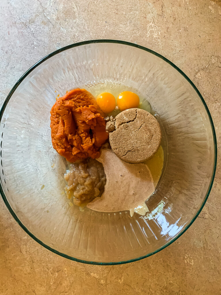 glass bowl with brown sugar, applesauce, sourdough starter, egg and pumpkin puree in piles inside the bowl