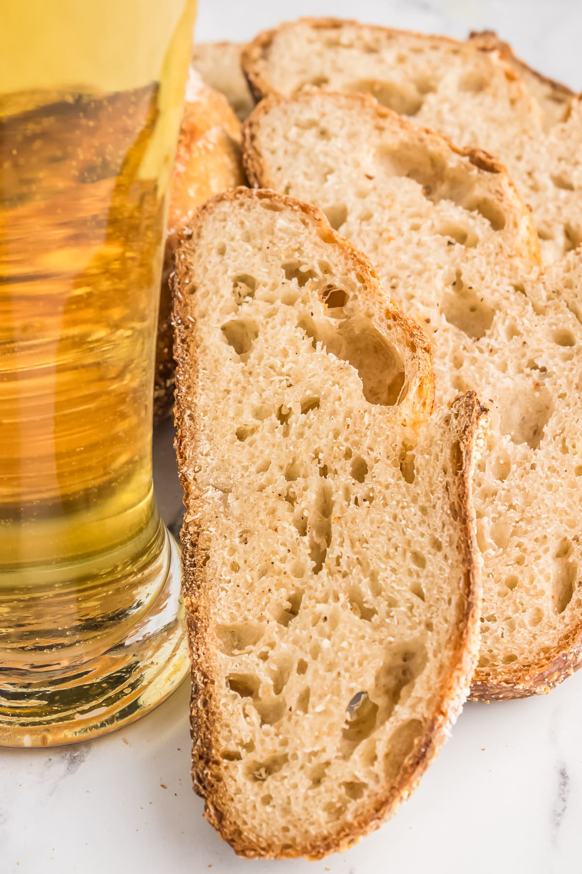sourdough beer bread sliced and stacked next to glass of beer