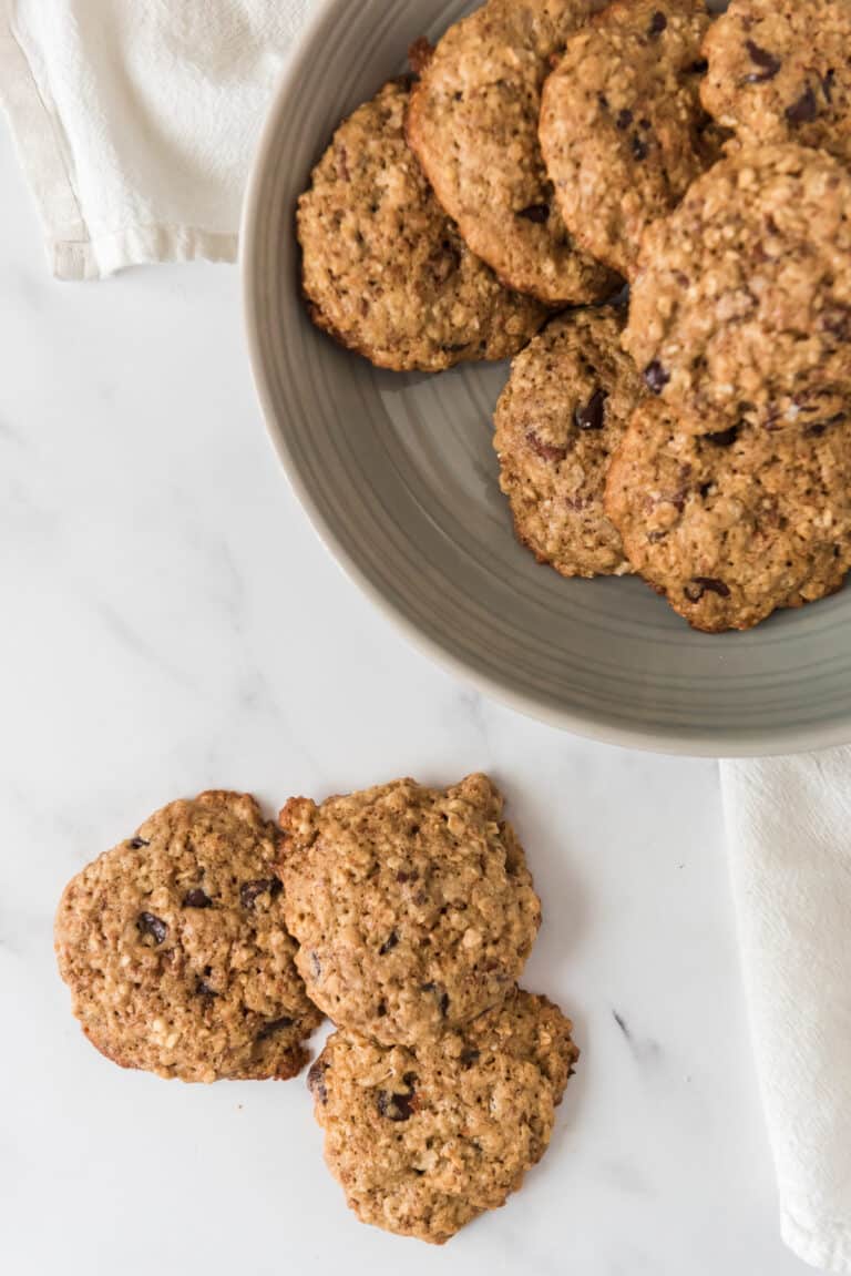 sourdough cowboy cookies scattered on counter with bowl of more beside