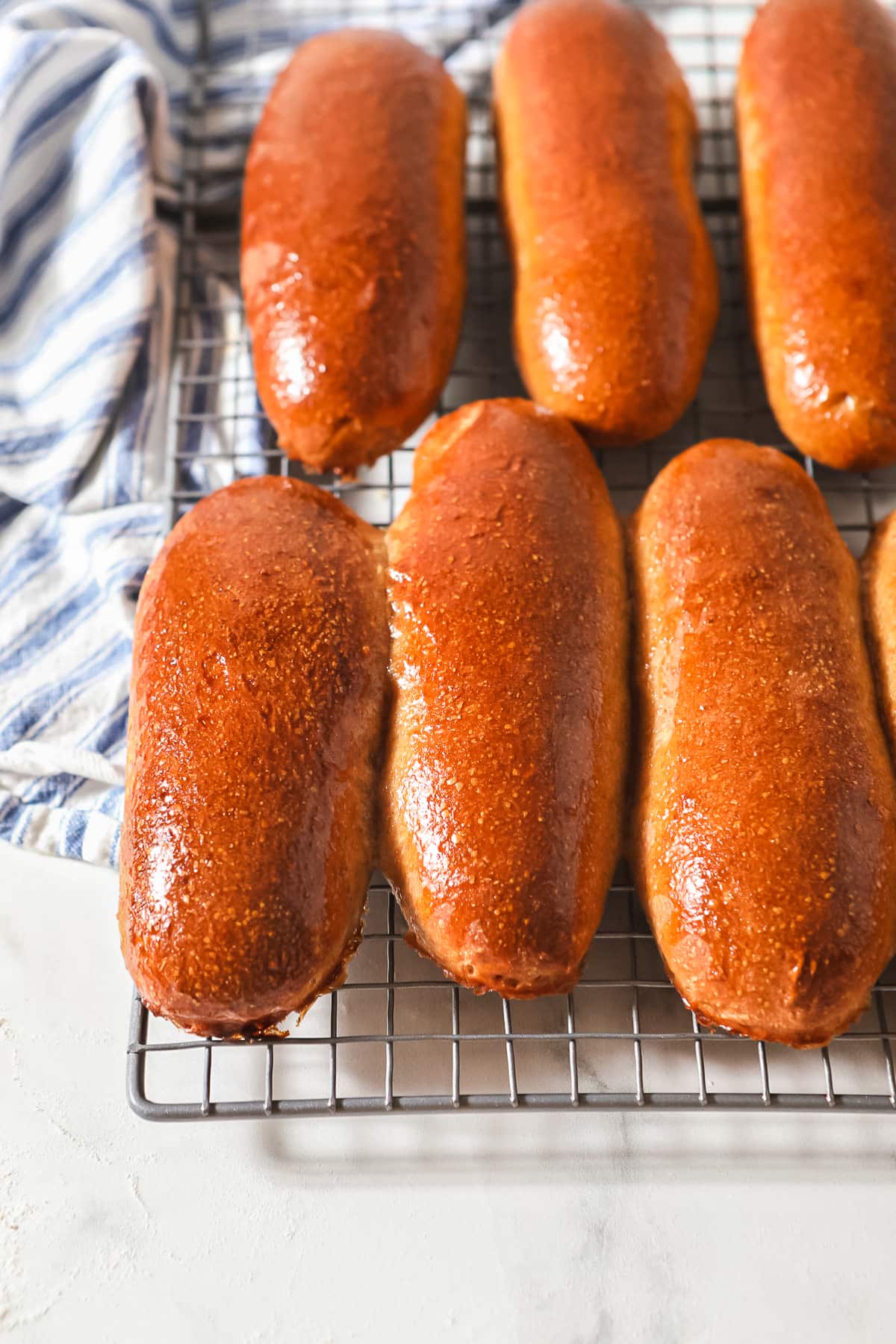 freshly baked sourdough hot dog buns cooling on wire rack