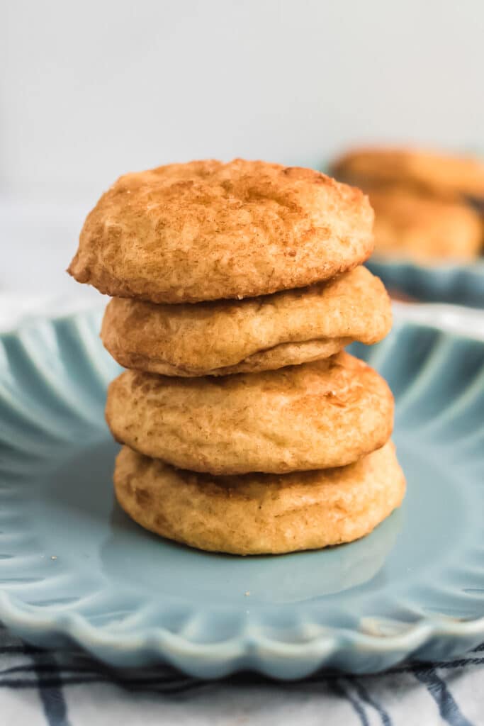 closeup of four sourdough snickerdoodle cookies stacked on a blue plate