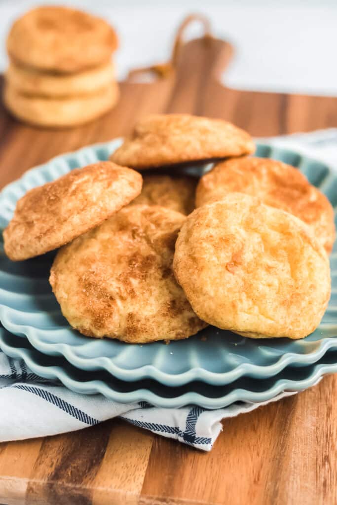 sourdough snickerdoodle cookies on blue plate with more cookies stacked in background