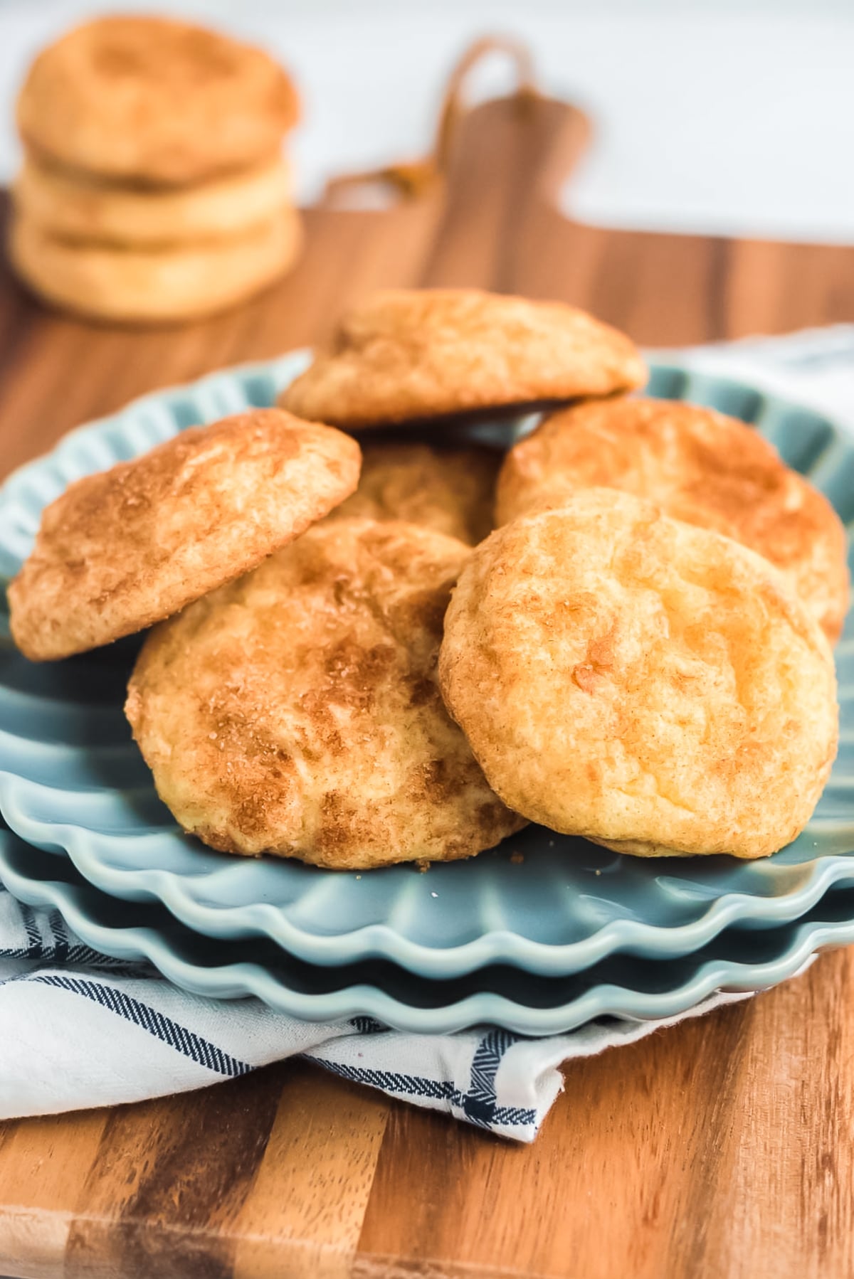 sourdough snickerdoodle cookies on blue plate with more cookies stacked in background