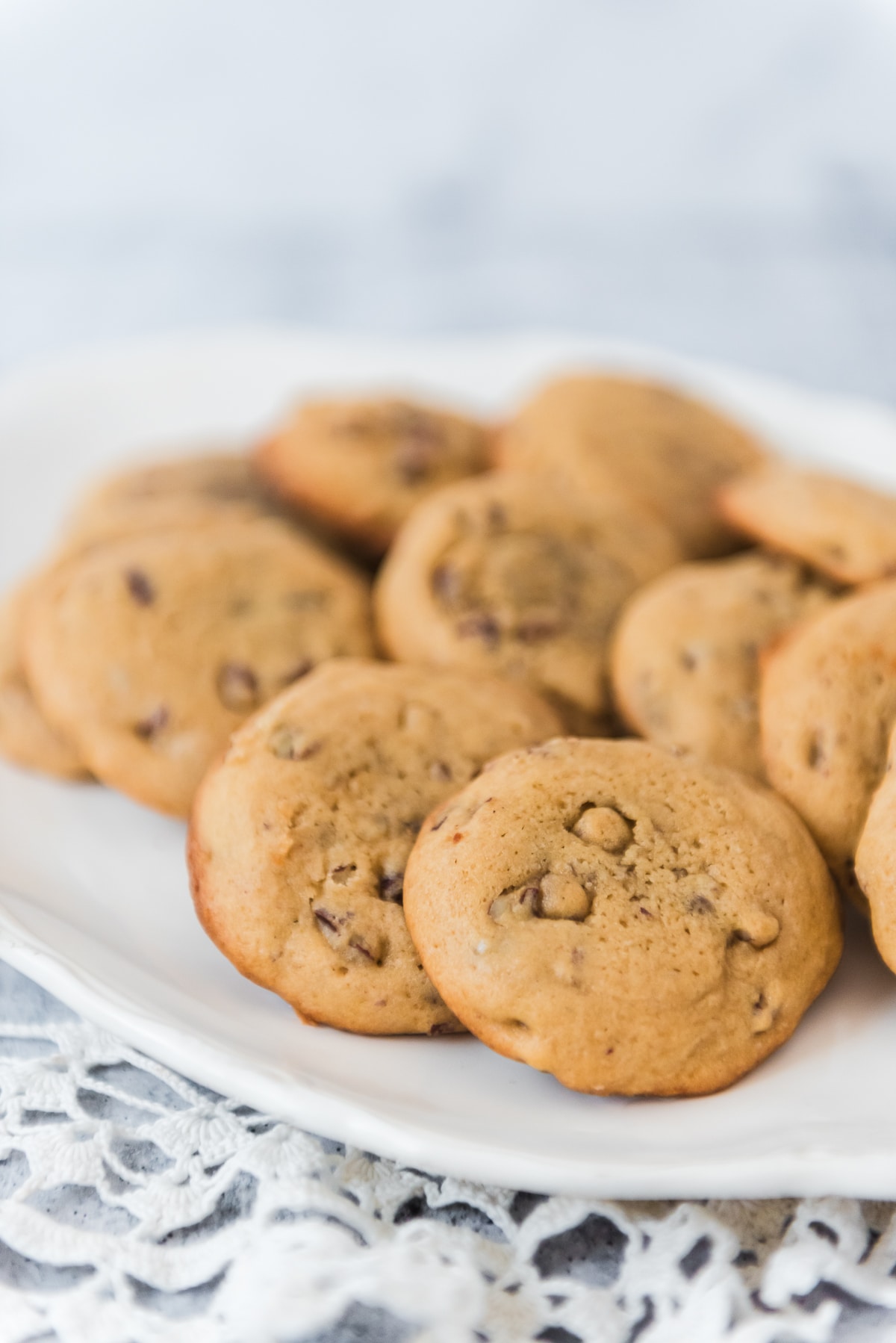 sourdough butter pecan cookies on white platter on lace doily