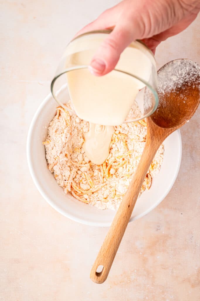 pouring milk into bowl of dried ingredients with butter