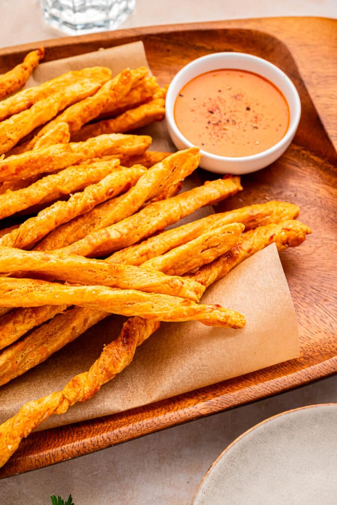 sourdough cheese straws on tray with dipping sauce beside