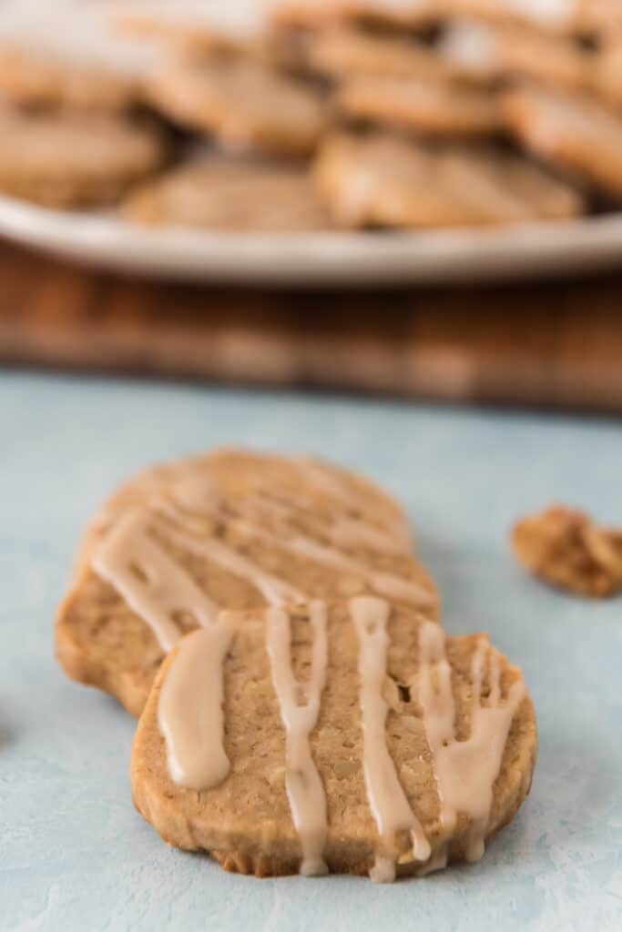 two maple walnut cookies wtih drizzle resting on each other with tray in background