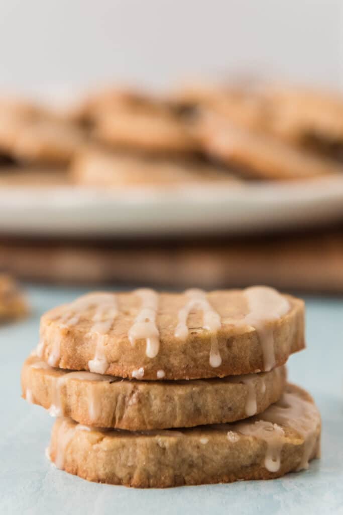 three cookies stacked with maple drizzling on top with cookie tray in background