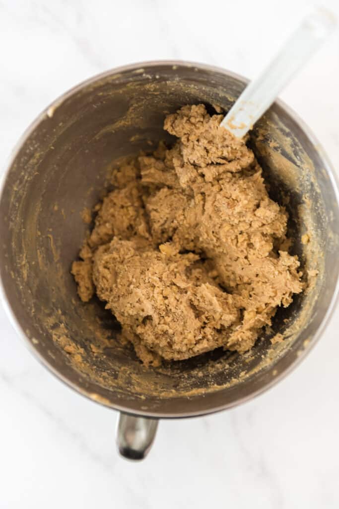 metal mixing bowl with cookie dough and white rubber spatula