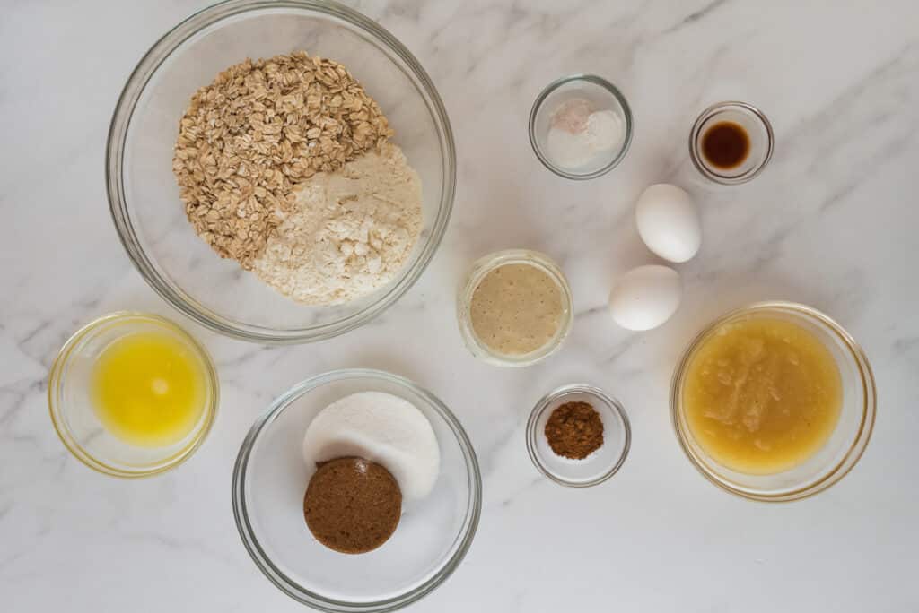 overhead view of glass bowls with ingredients for muffins on marble counter
