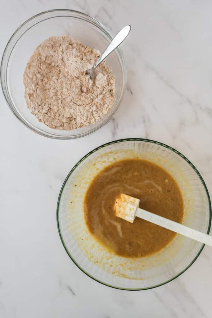 overhead of two glass mixing bowls - one with dry ingredients and one with wet ingredients and forks.