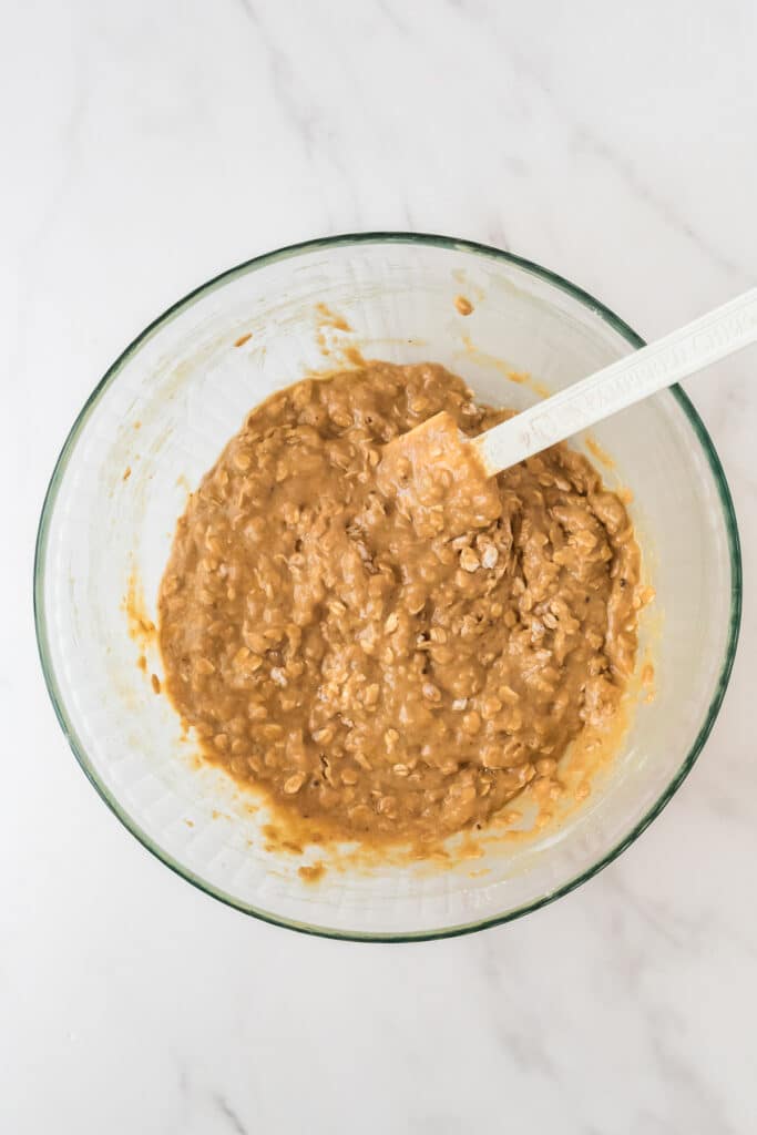 overhead of glass mixing bowl with sourdough muffin batter and white spatula