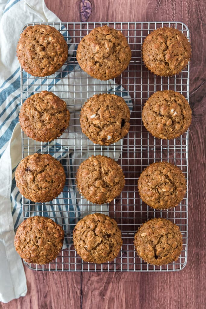 overhead of wire cooling rack with 12 sourdough applesauce muffins lined up in rows