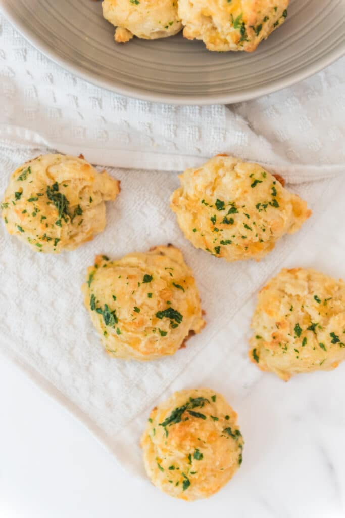 sourdough biscuits with cheddar, garlic and parsley on white kitchen cloth with grey bowl