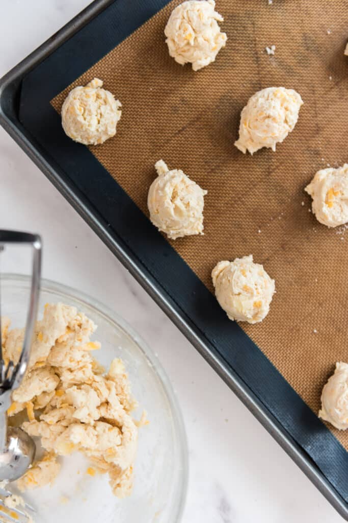 scooping drop biscuits into silicone lined baking sheet