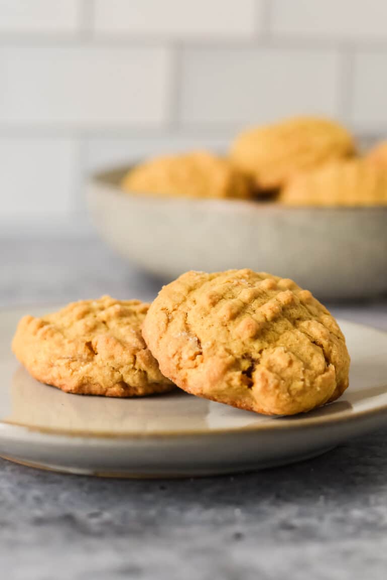 sourdough peanut butter cookies on a grey plate with bowl of more cookies in background