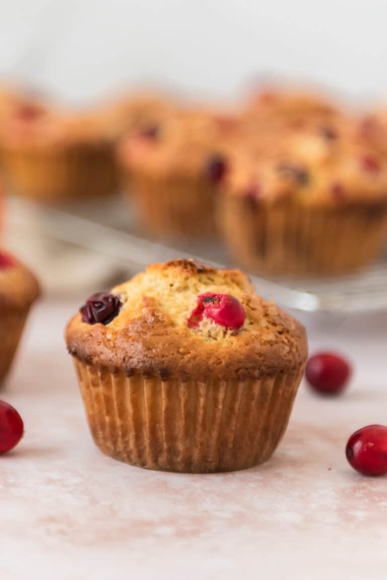 closeup view of sourdough cranberry orange muffin wtih more in background
