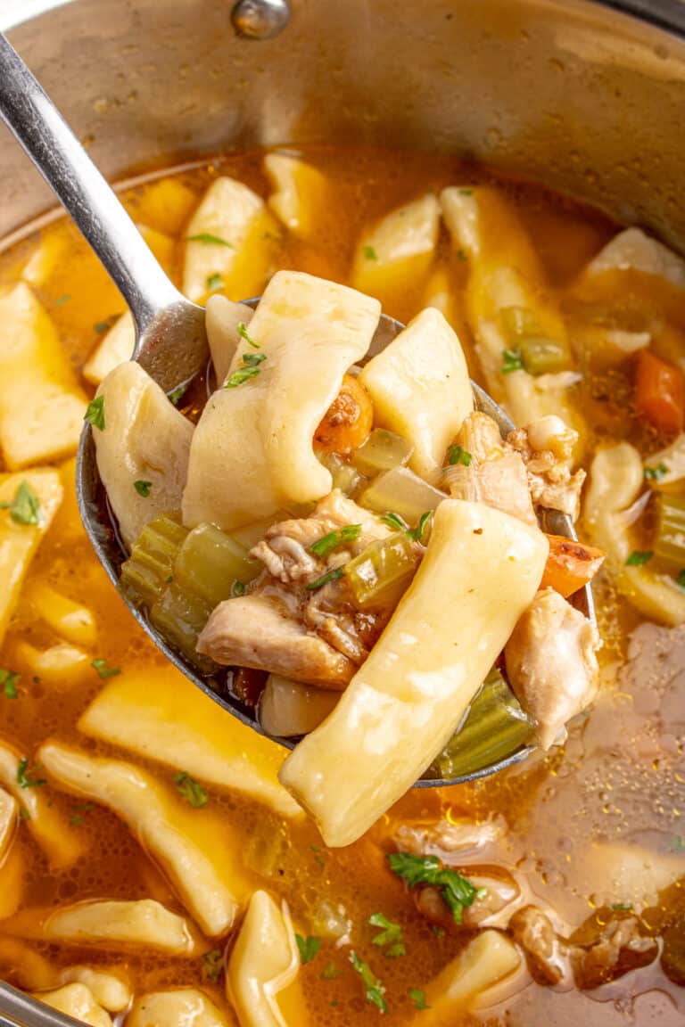 spoon full of sourdough egg noodles with background of broth and more noodles