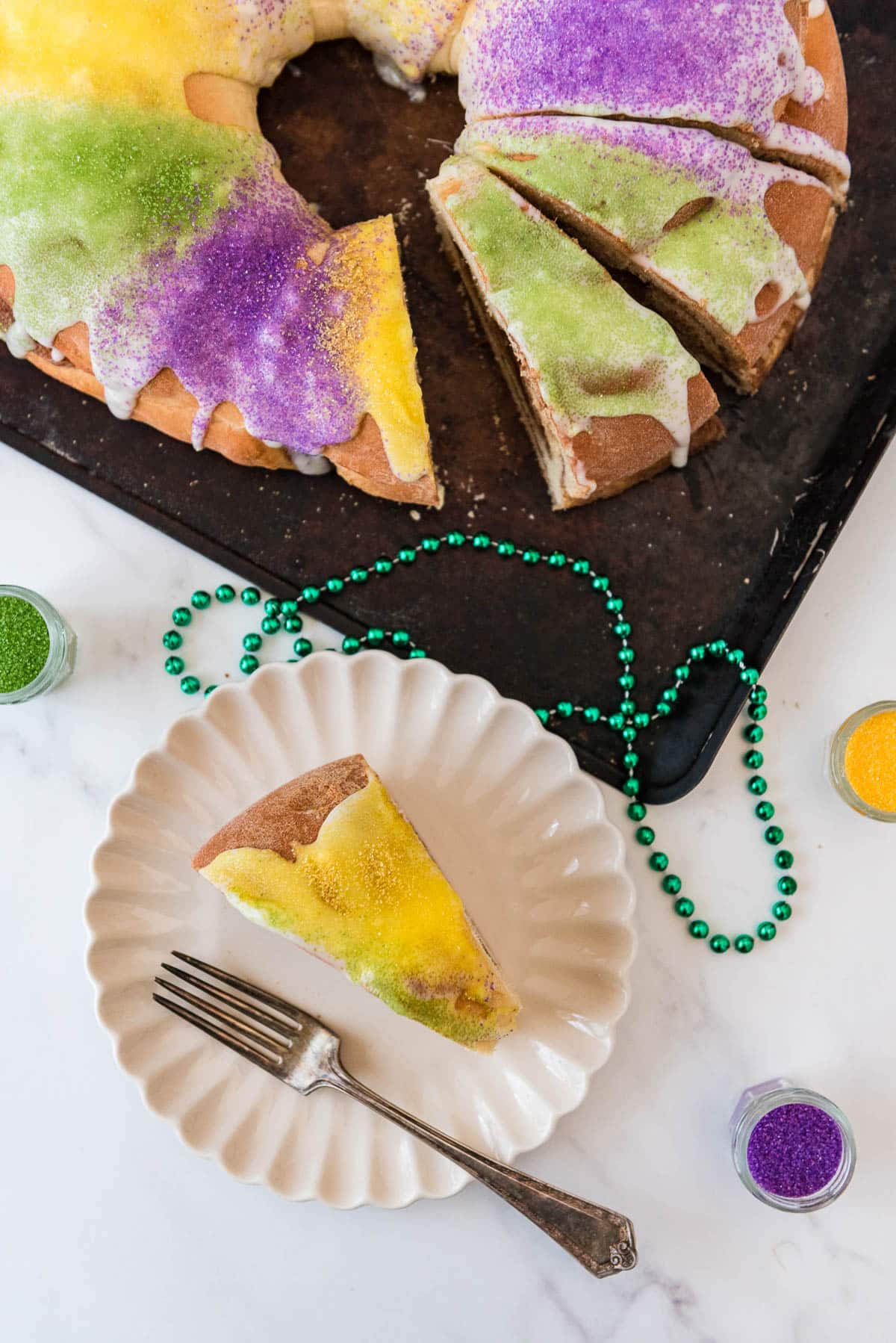 sourdough king cake overhead with one slice cut out and on white plate beside tray