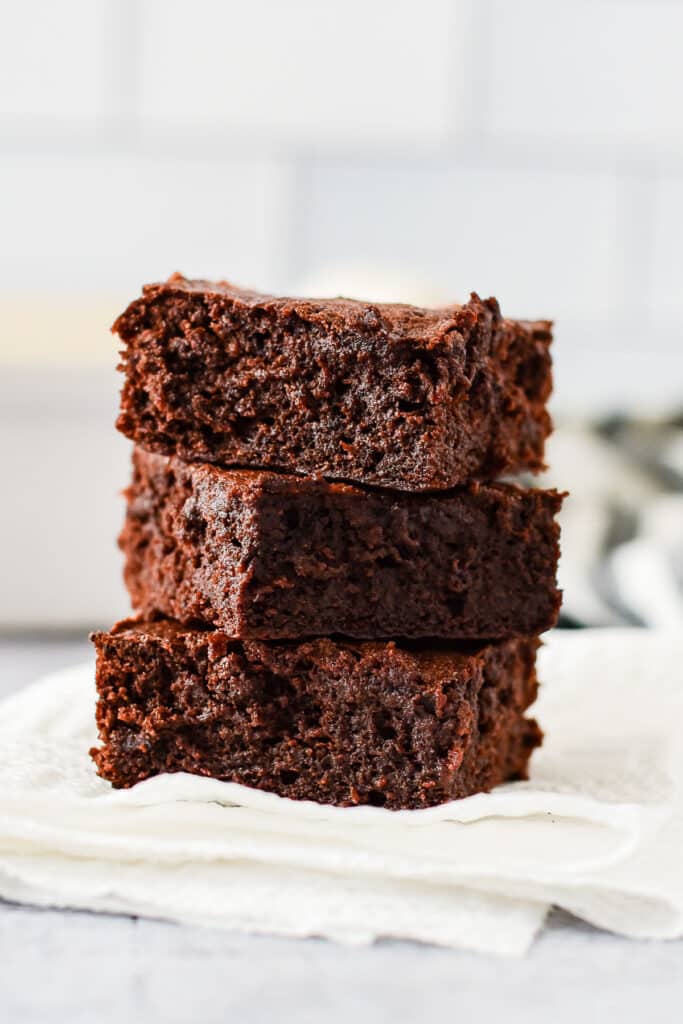 three sourdough brownies stacked on top of each other on folded piece of paper towel