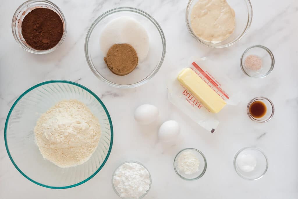 ingredients for discard crinkle cookies in glass bowls on marble counter