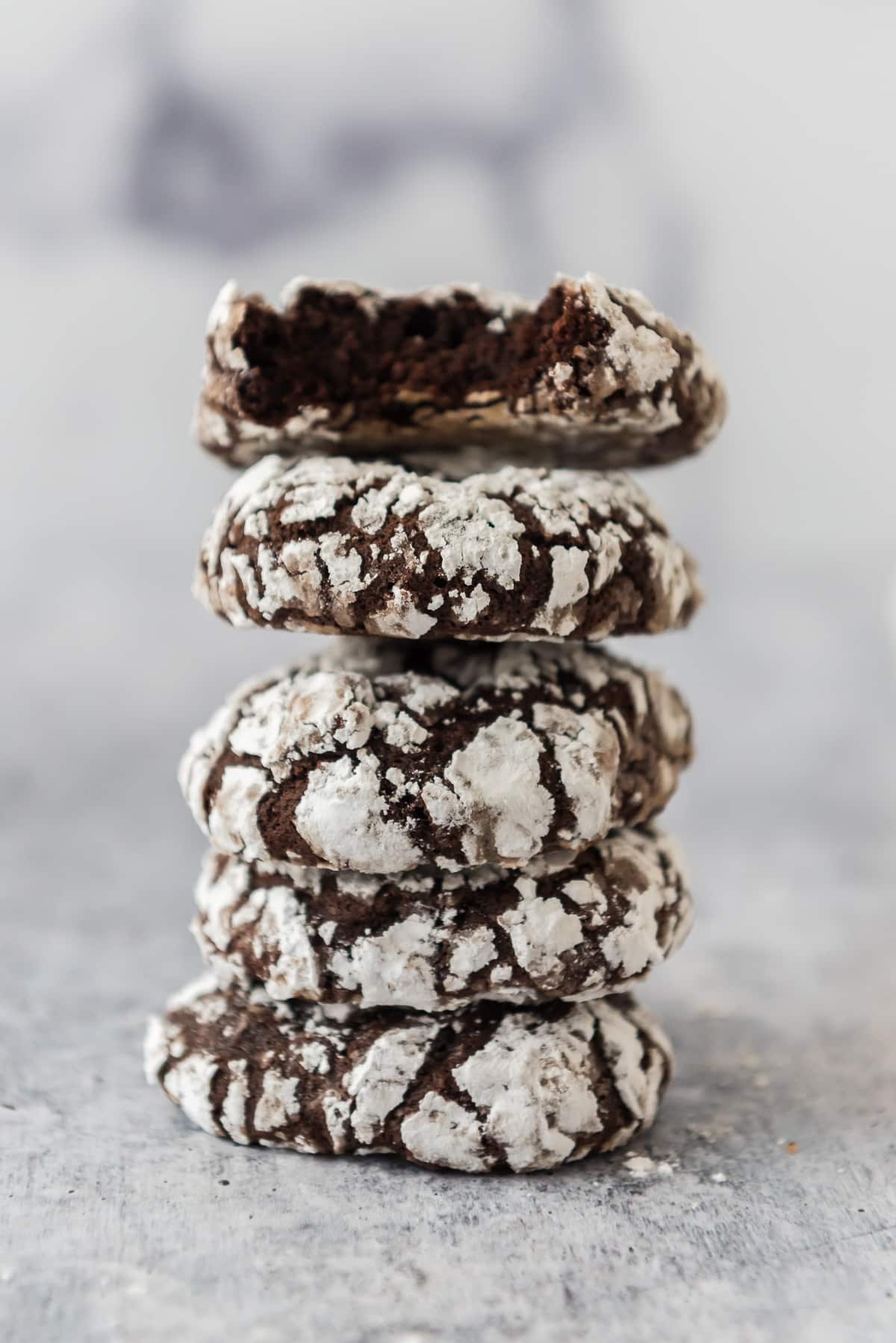 four sourdough chocolate crinkle cookies stacked together with bite taken out of top one