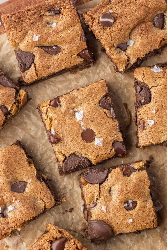 sourdough chocolate chip cookie bars on parchment paper sprinkled with flaky sea salt