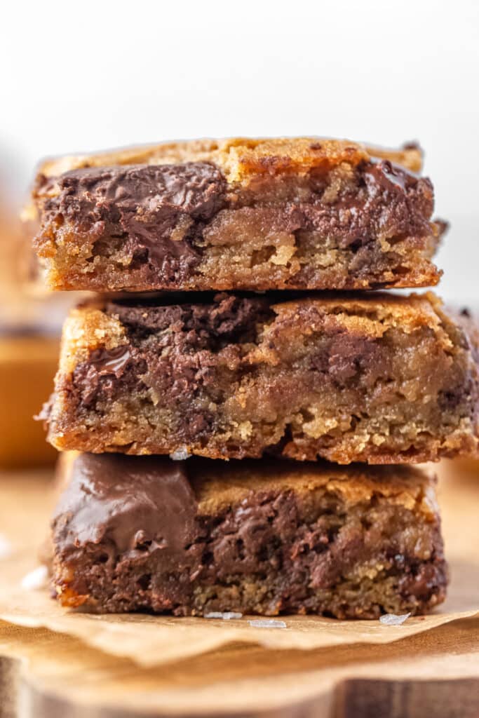 three sourdough chocolate chip cookie bars stacked on top of each other showing gooey centers