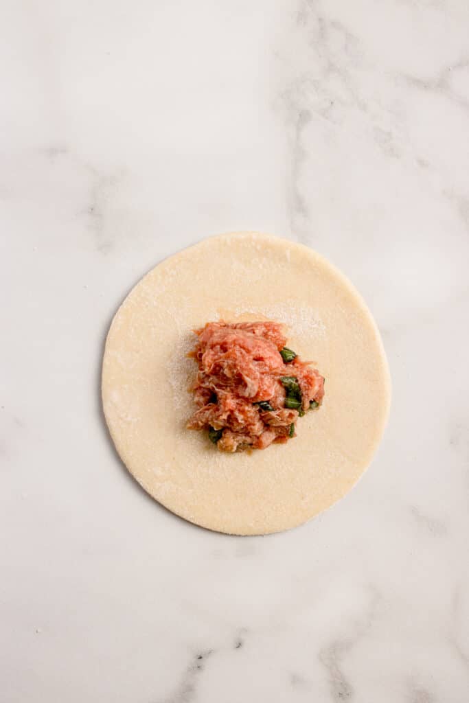 circle of dough with beef filling in center