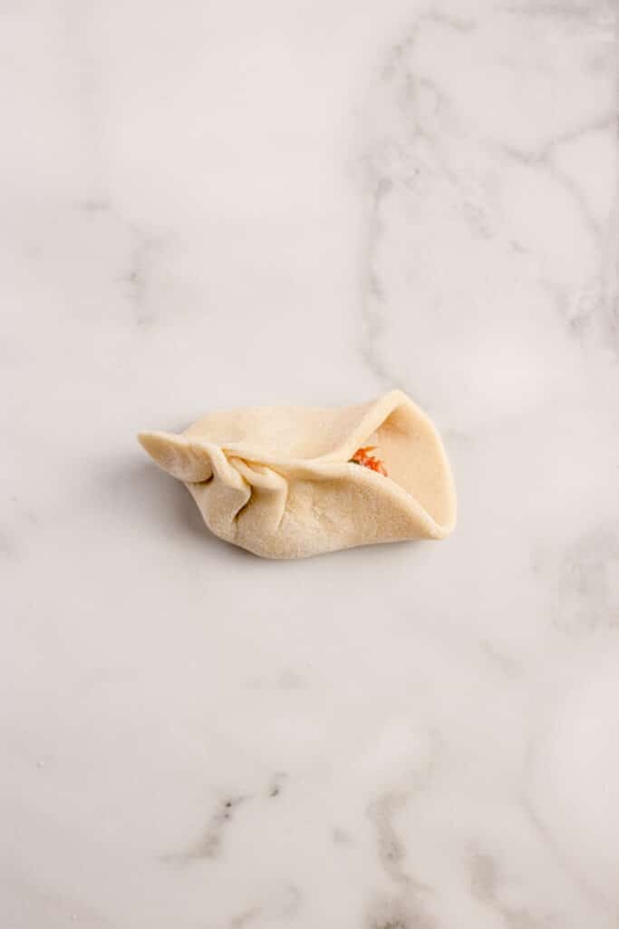 beef dumpling half folded showing crimping technique
