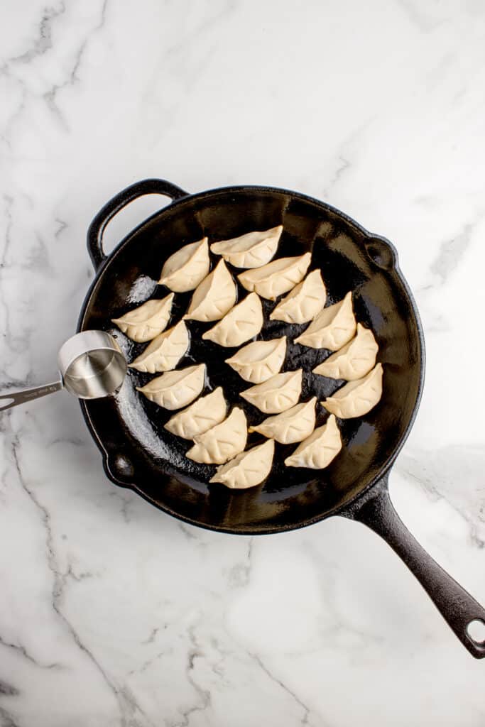adding water to cast iron skillet with dumplings