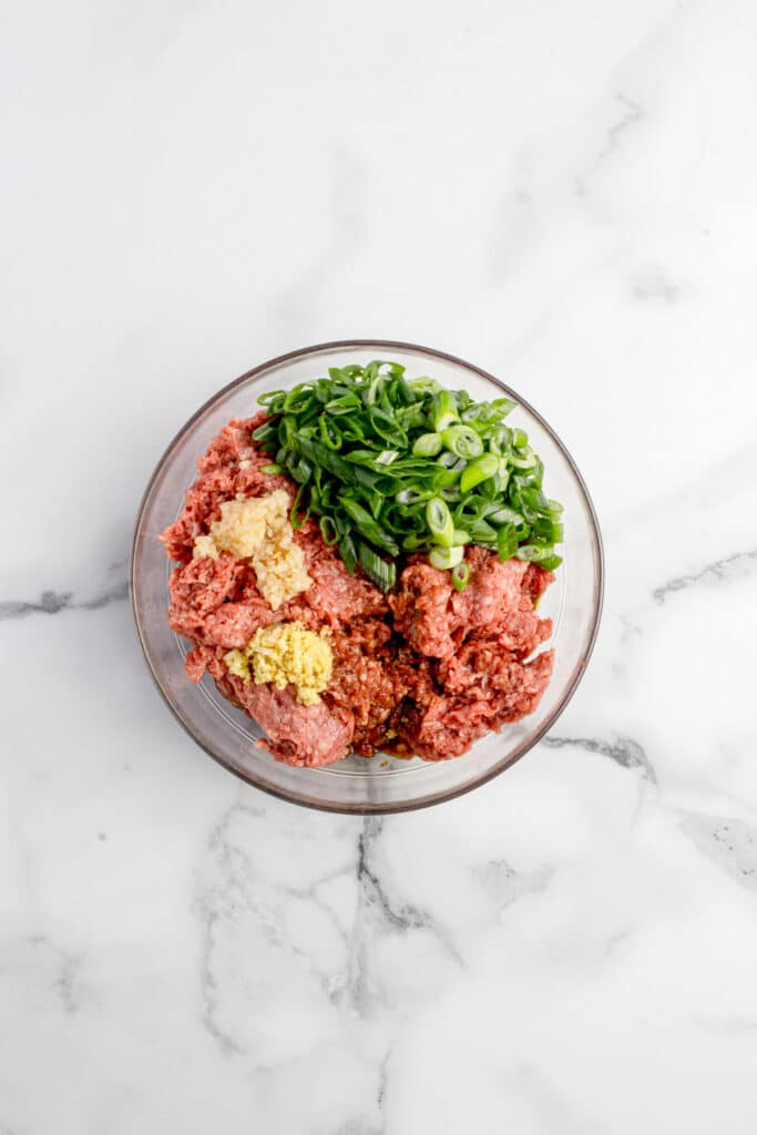 glass mixing bowl with ingredients for ginger beef dumpling filling