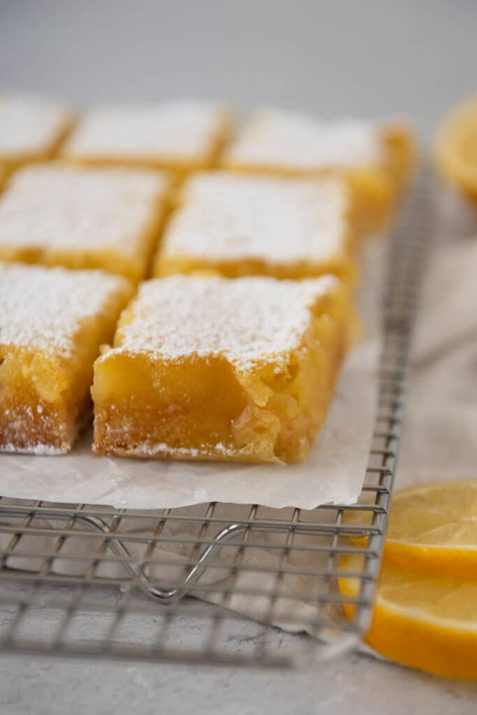 lemon bars squares with sourdough discard on wire cooling rack with powdered sugar on top