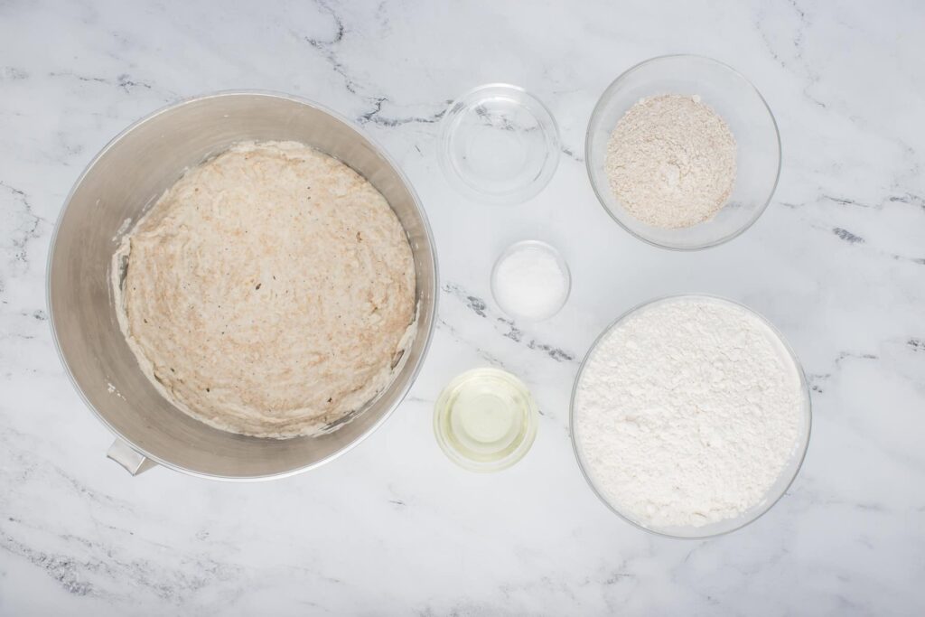 ingredients for sourdough ciabatta in glass bowls on marble counter