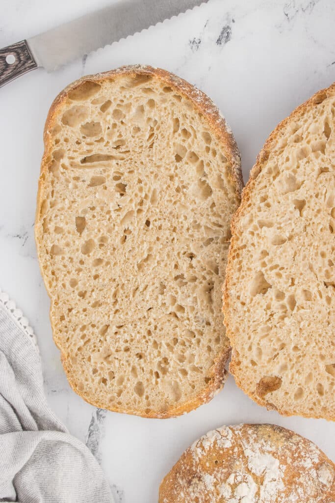 two loaves of sourdough ciabatta with one cut open showing texture inside bread