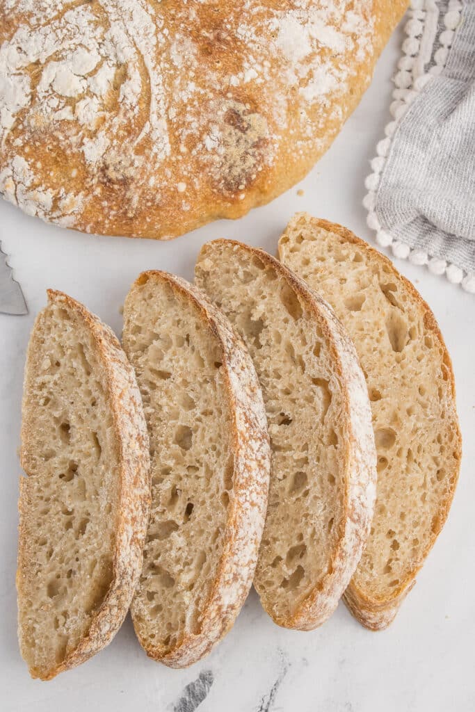 two loaves of sourdough ciabatta, the one in back whole and the one in front sliced into slices
