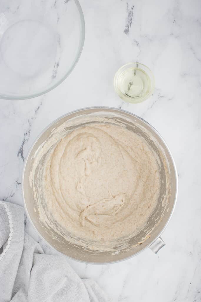 metal mixing bowl with mixed dough for ciabatta and oil in small bowl