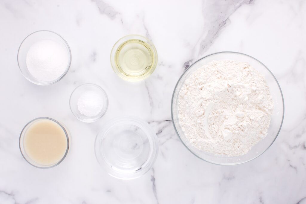 ingredients for potato flake sourdough bread on marble counter in glass bowls