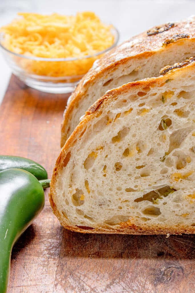 slices of jalapeno cheddar sourdough bread stacked together with jalapeno and cheddar cheese in background