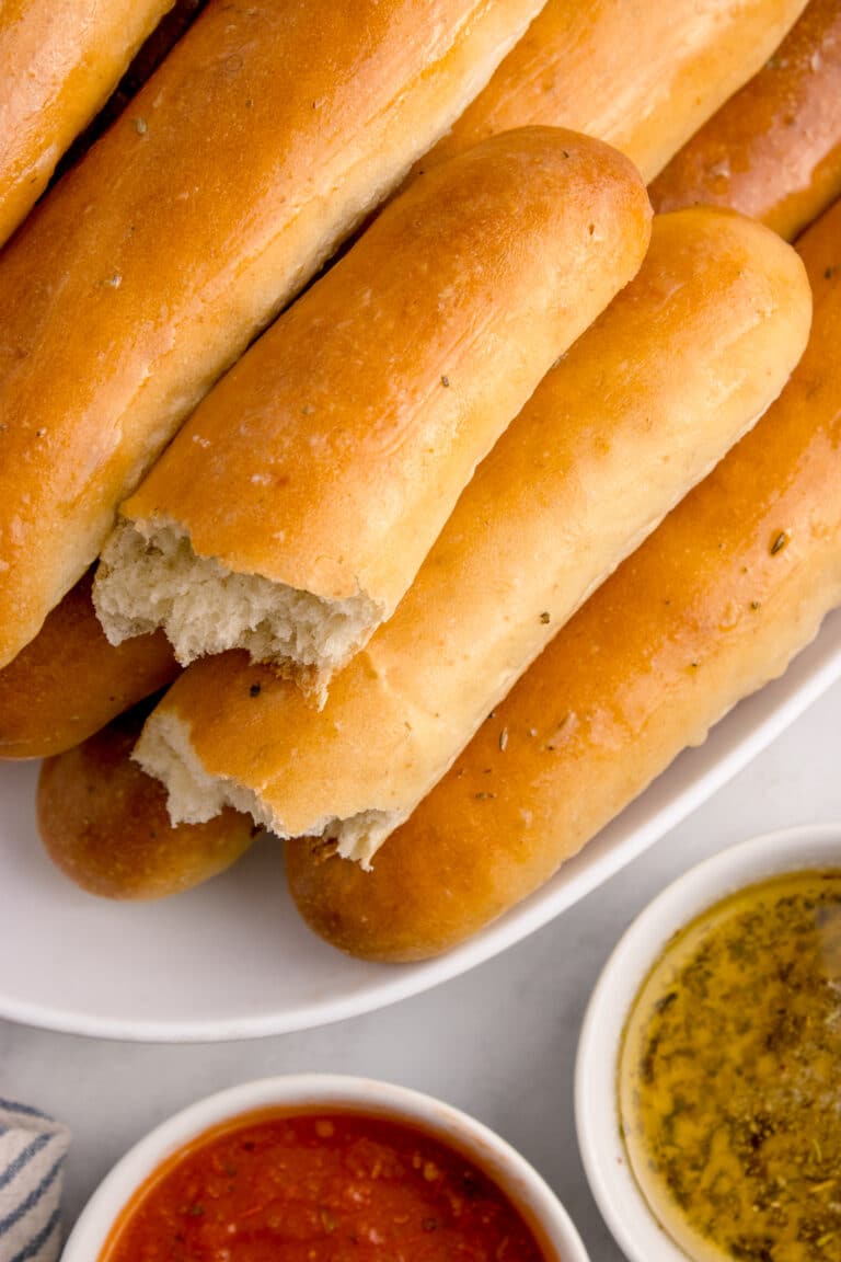 platter of sourdough breadsticks with one ripped in half.