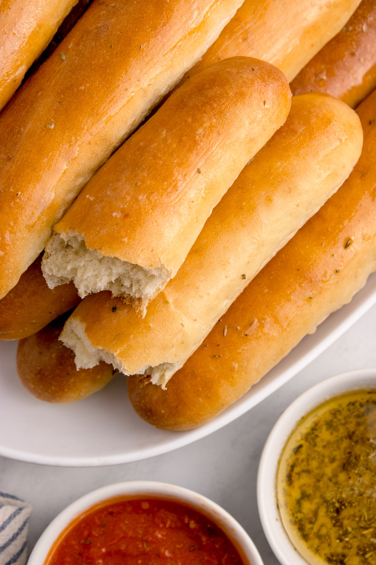 platter of sourdough breadsticks with one ripped in half.