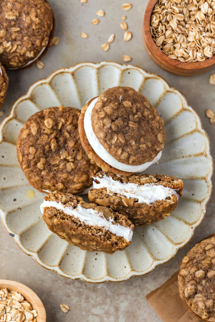 plate with sourdough oatmeal cream pie cookies, one cookie sandwich is spit open to show cream filling