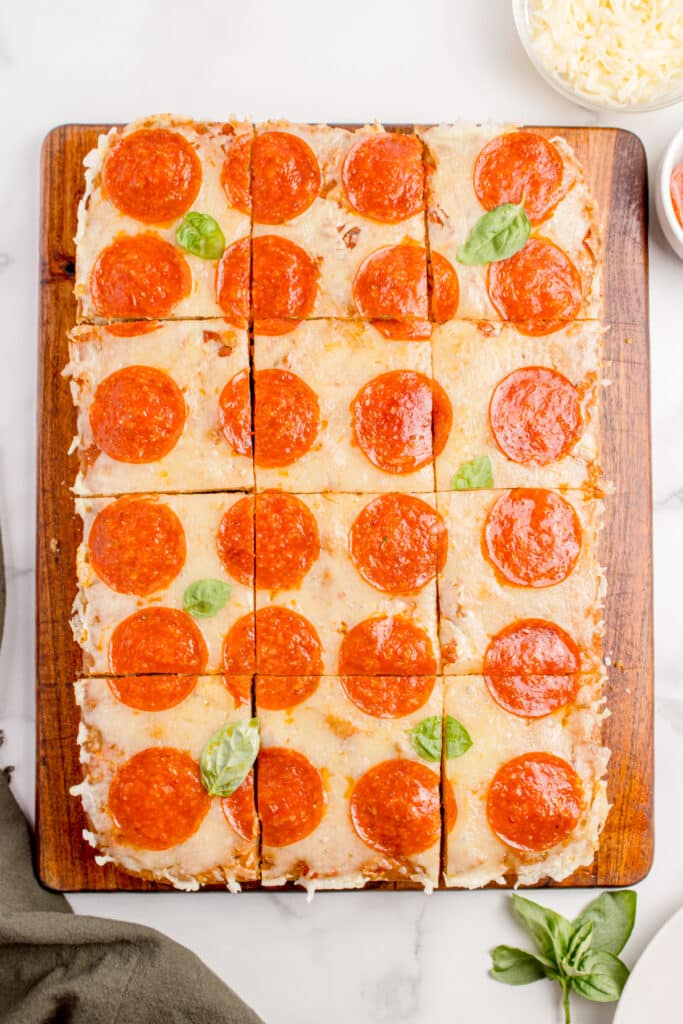 sourdough focaccia pizza with pepperoni and basil on wooden cutting board