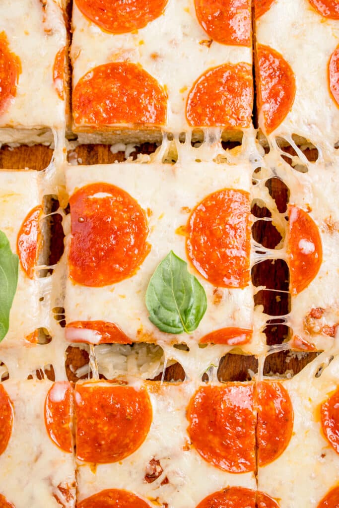 piece of sourdough focaccia pizza being lifted out to show cheese pull