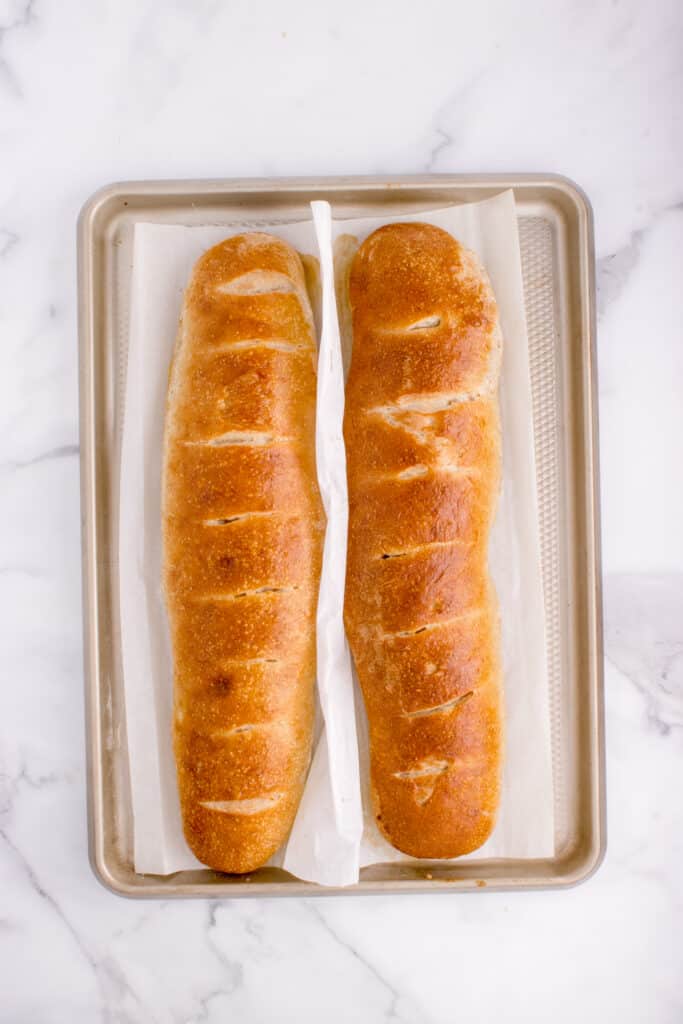 two loaves of freshly baked French bread on baking tray