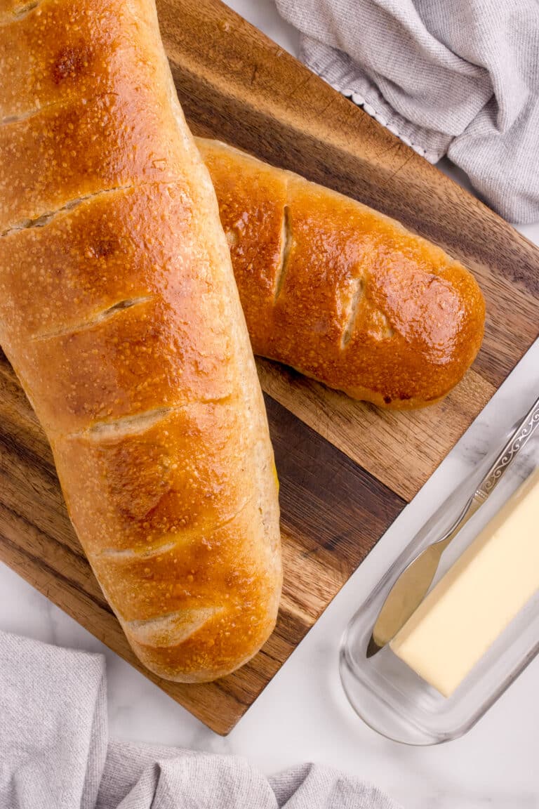 two loaves of sourdough French bread stacked on top of each other next to stick of butter