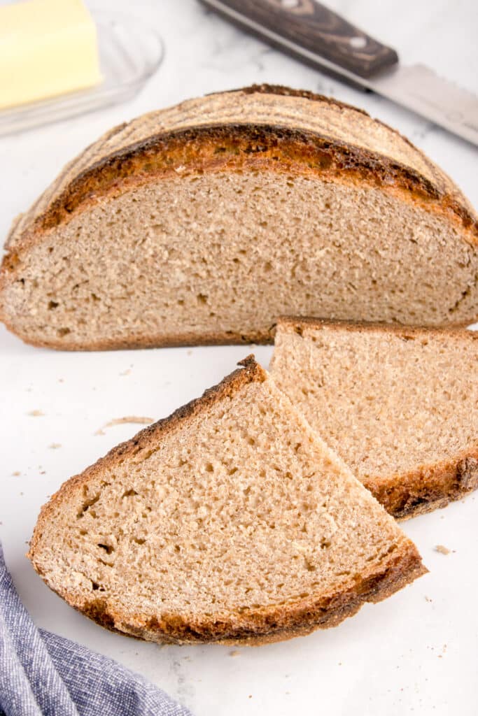 German sourdough rye bread loaf with slices stacked in front of remaining loaf