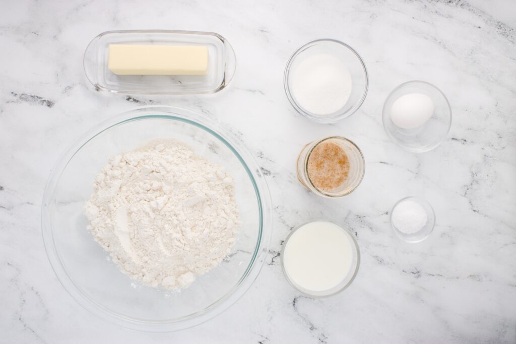 ingredients for sourdough brioche in glass bowls on marble counter