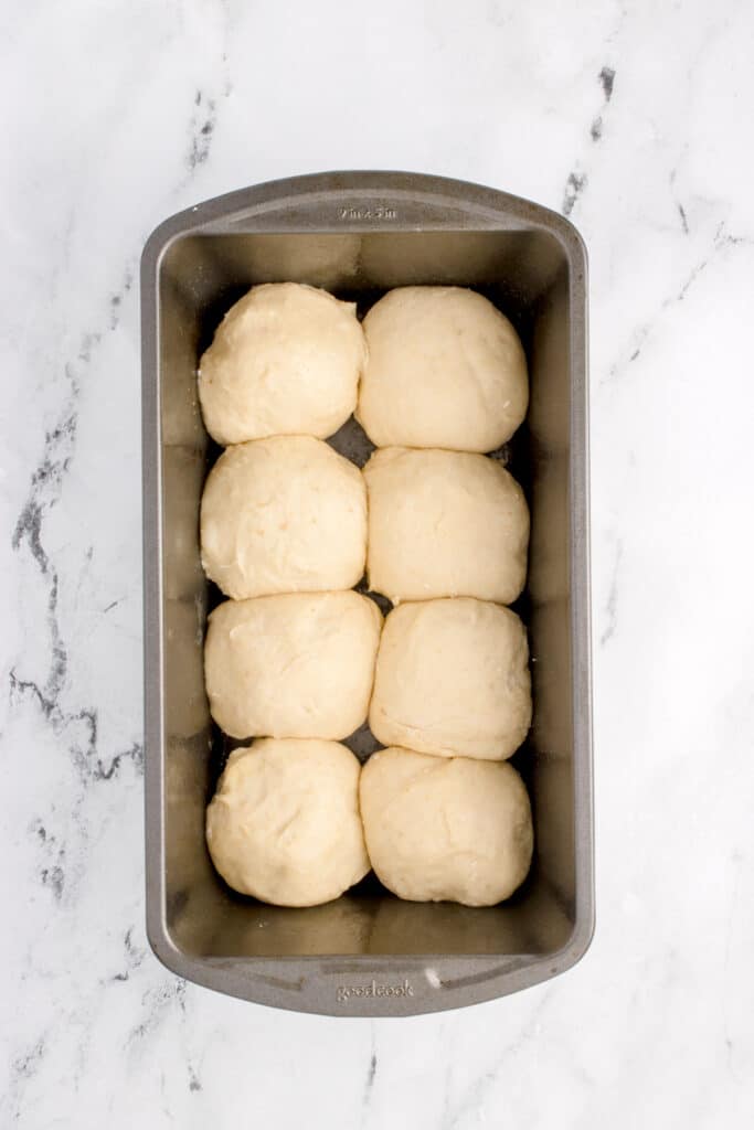 loaf pan with balls of dough for brioche